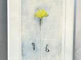 painting of a yellow flower in a white frame on a wall