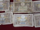 several old french currency notes are arranged on a red surface