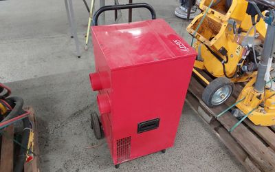 une machine rouge posée sur une palette, à côté d'une pile de palettes