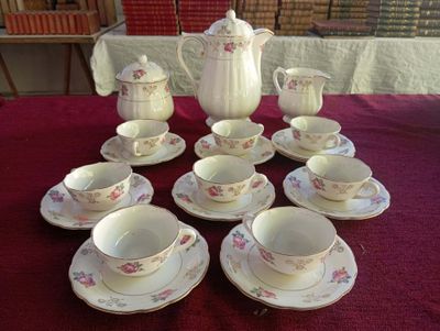 de nombreuses tasses et soucoupes posées sur une table recouverte d'une nappe rouge