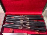 five knives in a case with a red cloth