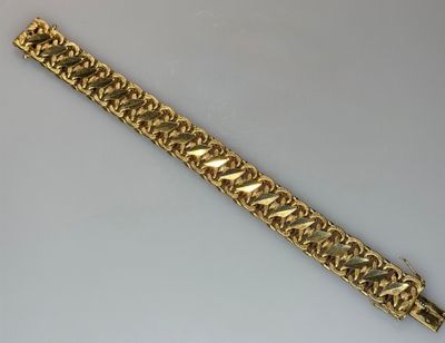 a close up of a gold bracelet on a white surface