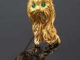 a close up of a gold dog broochle with green eyes