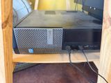 a computer sitting on top of a wooden shelf