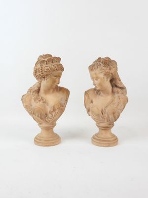 pair of carved busts of women on pedestals against a white background