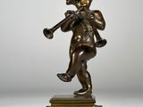 une figurine antique en bronze représentant un garçon jouant de la trompette