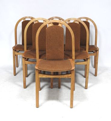 six wooden chairs with brown upholstered seats are arranged in a circle