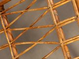 a wicker chair that has a wooden seat and back