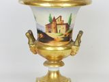 a gold and white vase with a painting on it