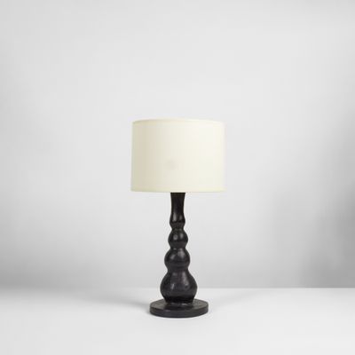 une lampe de table noire surmontée d'un abat-jour blanc