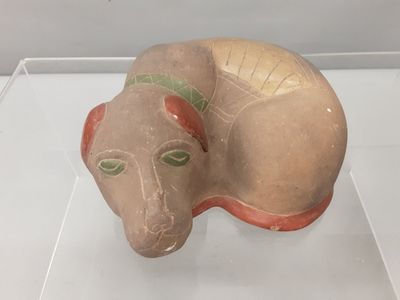sculpture of a cat with green eyes on display in a glass case