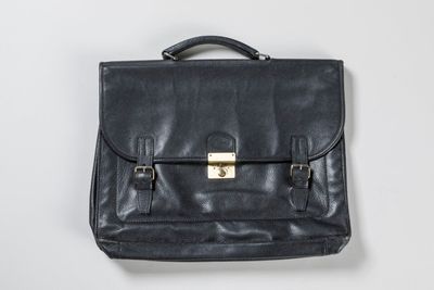 black leather briefcase with brass hardware on a white background