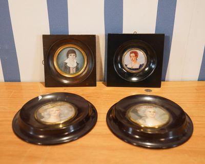 deux assiettes noires ornées d'images de femmes, posées sur une table en bois