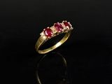une bague en or sertie de trois rubis sur un fond noir