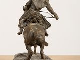 bronze statue of a man riding a horse with a dog on it