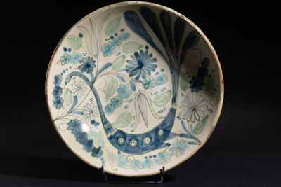 Plat circulaire en faïence à décor de paon dans les tons bleu et vert. - Photo 1