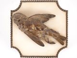 une image représentant un oiseau en bois est fixée sur une plaque