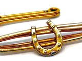 une paire de barrettes de couleur dorée avec un fermoir en forme de fer à cheval