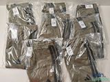 six paires de pantalons pour homme emballées dans du plastique, posées sur une table