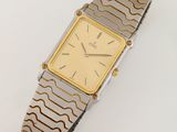 une image d'une montre-bracelet en or et argent sur une surface blanche