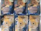 six paquets de café sont posés sur une table blanche