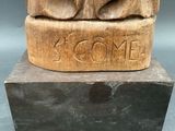a wooden statue of a bear with the word come carved on it