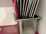 a lot of utensils in a metal container on the counter