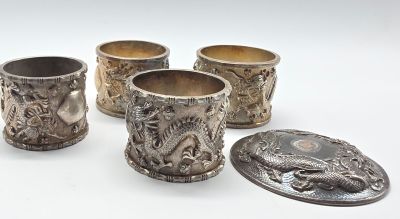 quatre coupes en argent ornées de motifs, posées sur une surface blanche