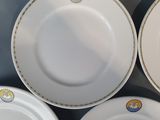 four white plates with gold trims are arranged on a table