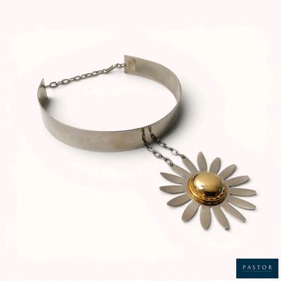 Collier avec une fleur en argent et en or, muni d'une chaîne, sur fond blanc