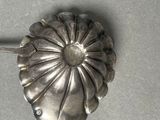 a silver spoon with a flower on it sitting on a table