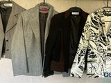 trois manteaux accrochés à un mur, à côté d'un porte-manteau