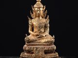 une statue en or représentant une personne assise sur une surface noire