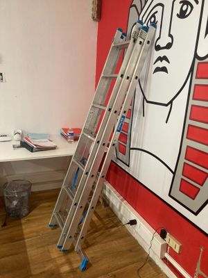 a ladder leaning up against a wall with a painting of a man on it