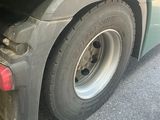 a green truck with a flat tire parked on the side of the road