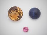 three different colored gems are displayed on a white surface