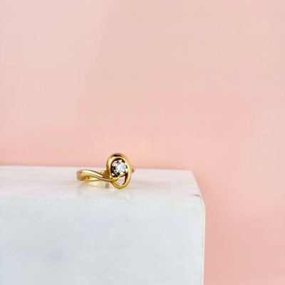 un gros plan d'une bague en or sertie d'un diamant noir posée sur un bloc de marbre blanc