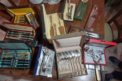 a lot of silverware on a table with a person standing next to it