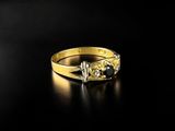 a yellow gold ring with two diamonds on a black background