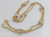a gold chain necklace with pearls on a white background