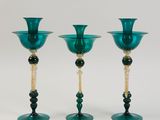 three green glass candlesticks with beaded stems on a white background