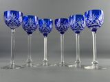 six blue wine glasses lined up in a row on a gray surface