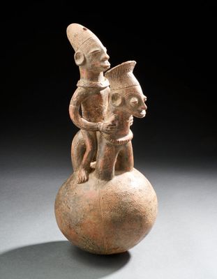 une figurine ancienne représentant un homme et une femme assis sur une boule
