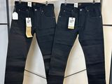 deux paires de jeans noirs suspendues à un portant dans un magasin