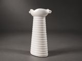 un vase blanc surmonté d'un oiseau