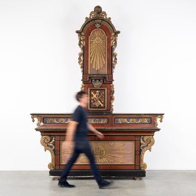 un homme passant devant une grande horloge en bois dans une pièce