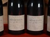 three bottles of red wine are lined up on a table
