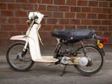 a white motor bike parked in front of a brick wall