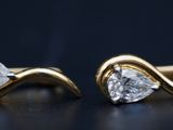 une paire de boucles d'oreilles en or et diamants posée sur un fond noir