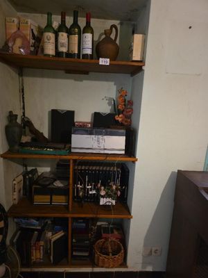 une petite pièce avec une étagère remplie de bouteilles de vin et d'autres objets
